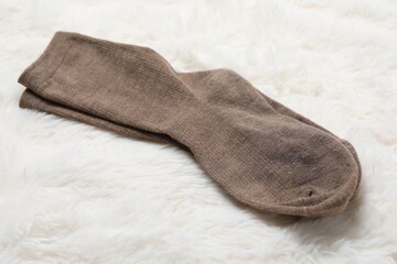 Pair of soft socks on white faux fur, closeup