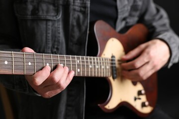 Fototapeta premium Man playing guitar on black background, closeup
