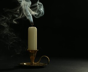 Extinguished candle in candlestick on black background, space for text