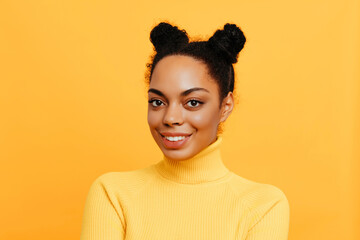 Cheerful African American woman with natural curly hair styled in two buns, wearing a yellow turtleneck sweater, posing confidently against a bright background.
