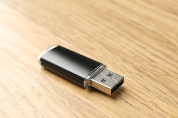 One flash drive on wooden background, closeup. Space for text