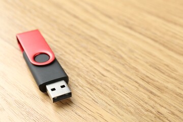 One flash drive on wooden background, closeup. Space for text