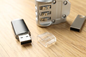 Flash drives and combination padlock on wooden background, closeup