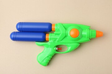 Bright plastic water gun on beige background, top view