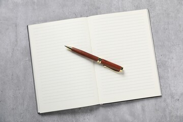 Pen and open notebook on grey table, top view