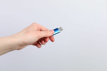 Man with modern flash drive on light grey background, closeup. Space for text