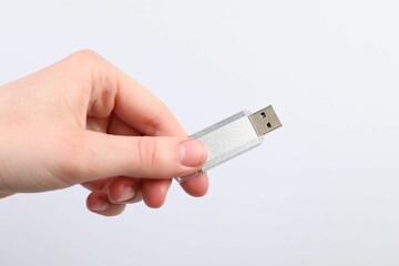 Man with modern flash drive on light grey background, closeup
