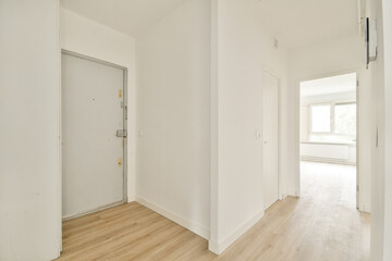 A bright, modern hallway featuring light walls and wooden flooring, showcasing a simplistic design approach with a sense of spaciousness and clarity.