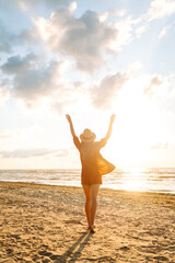 Back view of a young woman with curly hair feels free on the seashore. Young woman walks on the...