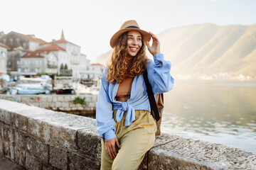 A female traveler in a straw hat is walking along a picturesque harbor. Young woman enjoys the...