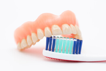 Cepillo de dientes limpiando una dentadura, aislado en blanco