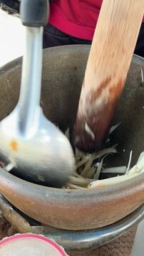Unidentified chef is pounding ingredients in a mortar to make som tam, Thai favorite street food.
