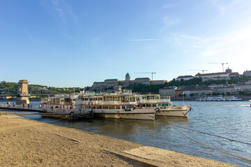 Cruise boats docked on the Danube River in Budapest with view of Buda Castle and Chain Bridge in the background, photographed on April 14, 2024