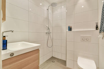 A sleek and contemporary shower space featuring white tiles, a stylish sink, and a glass shower setup that emphasizes simplicity and elegance.