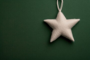 Soft white star ornament hanging against deep green background e