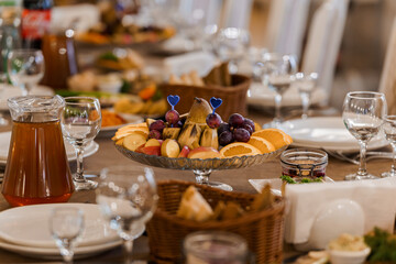 Festive Breakfast Table Setting with Abundant Food and Stylish Glassware Featuring a Fruit Platter, Baskets, Drinks, and Elegant Place Settings
