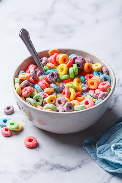 Colorful fruit cereal in bowl on white marble background.