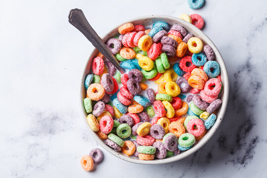 Colorful fruit cereal in bowl on white marble background.