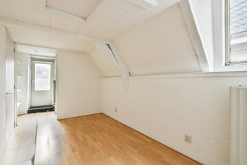 A bright, minimalist interior space featuring white walls and wooden flooring, emphasizing simplicity and tranquility with ample natural light.