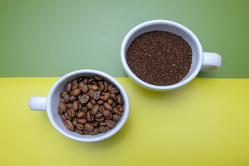 Two Coffee Cup Filled with Ground Coffee and Beans on Colorful Background