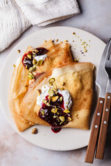 Breakfast crepes with sour cream, jam and pistachio.