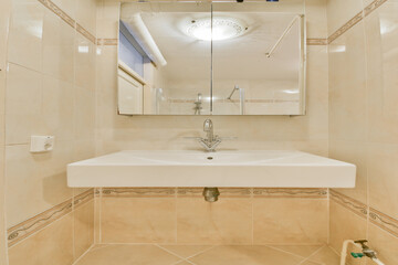 A sleek and contemporary bathroom featuring a spacious sink area and a striking large mirror. The tiles are arranged elegantly, enhancing the overall aesthetic.