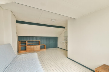 A cozy space featuring a blue accent wall and light-colored flooring. The room is furnished simply with a light sofa and wooden storage, creating a tranquil atmosphere.
