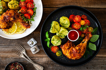 Oven roasted chicken leg with boiled potatoes, fresh tomato salad and ketchup on wooden table	