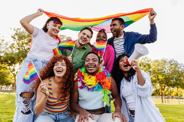 Happy multiethnic activists celebrating gay pride holding rainbow flags and megaphone