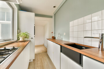 A stylish modern kitchen featuring minimalist cabinetry, a wooden countertop, and ample natural light streaming through large windows.