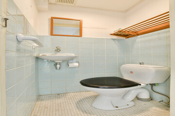 A neat bathroom featuring light blue tiles, a modern toilet, a sink, and a mirror, providing an inviting and fresh atmosphere for personal care.
