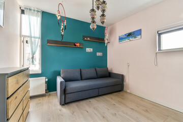 A contemporary living room featuring a stylish gray sofa, vibrant teal wall, and decorative elements that enhance the inviting atmosphere.