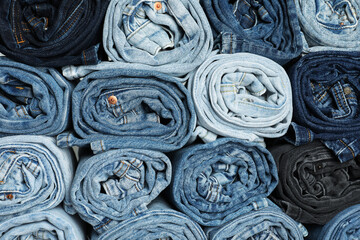 Different stylish rolled jeans as background, top view