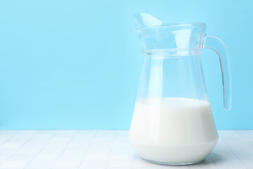 Fresh milk on white table against light blue background. Space for text