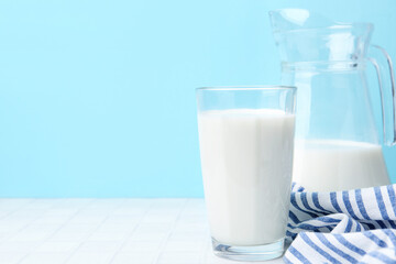 Fresh milk on white table against light blue background. Space for text