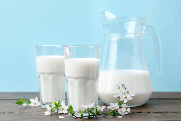 Fresh milk and blossoms on white table against light blue background
