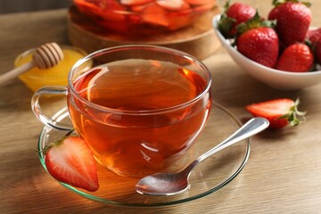 Aromatic fruit tea with strawberries and honey on wooden table, closeup