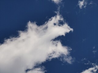 Large white cloud with sharp, irregular edges stretches across a deep blue sky, creating a dramatic and vivid natural background