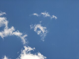 Thin, scattered wispy clouds float against a vivid blue sky, creating an airy, peaceful, and open atmosphere suitable for natural background use