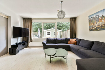 A modern living room featuring a sleek design with a comfortable sofa, coffee table, and a view of a garden through large windows.