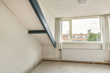 A vacant room featuring large windows that let in ample natural light. The minimalist design includes light-colored walls and simple furnishings.