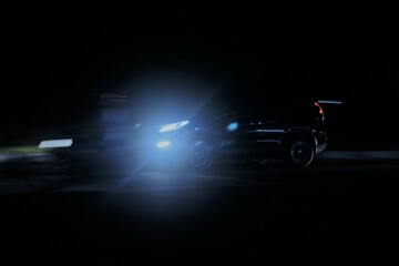 Obraz premium Car driving fast at night with headlights shining bright