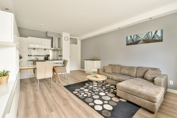 Stylish modern interior featuring a comfortable gray sofa, coffee table, and a chic dining area, complemented by minimalist design elements.