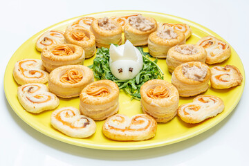 A hard-boiled egg in the shape of a bunny, surrounded by small puff pastry filled with salmon and tuna cream
