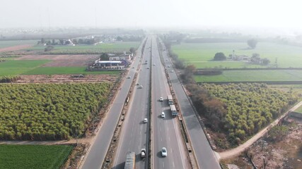 Light traffic moving on a 4 lane highway crossing through a agriculture fields.