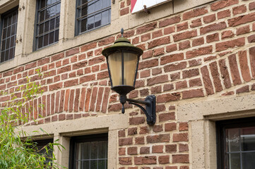 Old lamp hanging on a brick wall with decorative windows