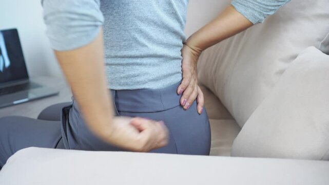 woman experiencing pain in the buttock and lower back from sciatic nerve issues or piriformis syndrome, caused by poor posture while working at a computer for long time 
