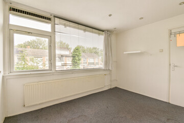 A spacious, bright room showcasing large windows, minimal decor, and a neutral color palette, ideal for a modern living space or office setup.