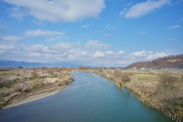 River and fields under blue sky and white clouds