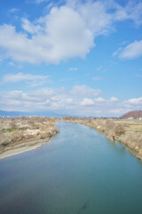 River and fields under blue sky and white clouds